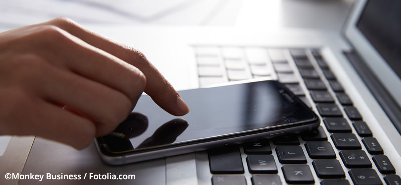 Close Up Of Person At Laptop Using Mobile Phone