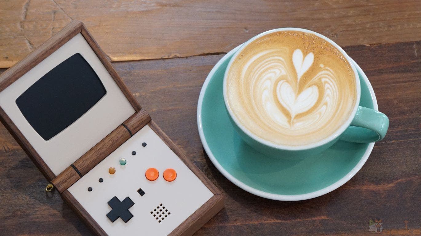 Pixel Vision auf einem Holztisch, daneben eine Tasse Kaffee