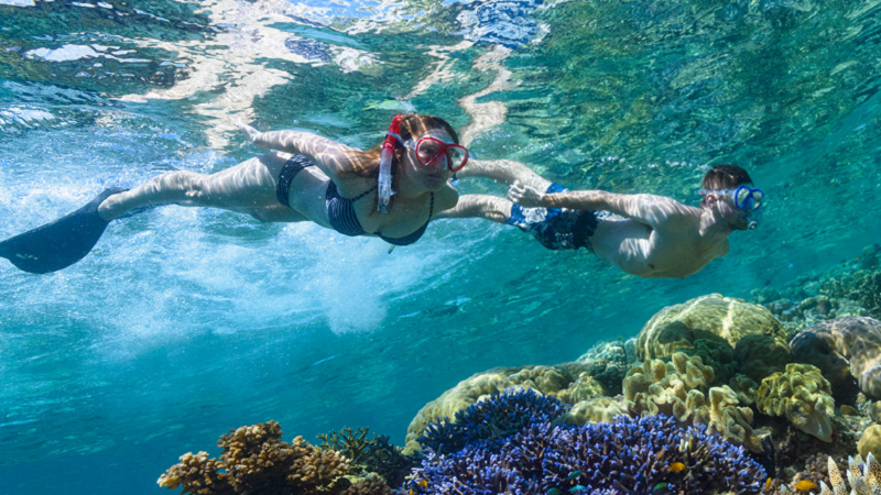 Mann und Frau mit Schnorcheln unter Wasser mit Korallenriff